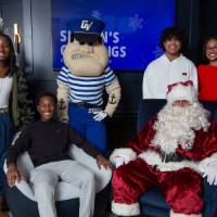 Four teenagers smile with Santa and Louie